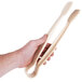 A hand holding Thunder Group beige polycarbonate flat grip tongs.
