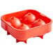 A red silicone ice mold with four round spheres inside.