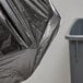 A black Lavex Hercules trash bag with a crease placed on a trash can.