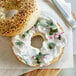 A bagel with Violife Just Like Cream Cheese and sesame seeds on a white background.
