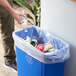 A person putting a Lavex Li'l Herc clear trash bag into a trash can.