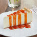 A slice of cheesecake with Capora Pumpkin Pie flavoring sauce on a plate.