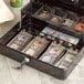 A black Point Plus cash box with money in it on a counter.