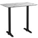 A white marble rectangular bar height table with black legs.