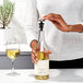 A person using an OXO wine stopper to close a bottle of white wine.
