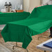 A person using a Hoffmaster jade green table cover on a table.