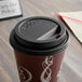 A Dart black coffee cup lid with a sip hole on a coffee cup.