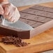 A person cutting Callebaut dark chocolate with a knife.