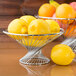 A wire basket of lemons on a counter.