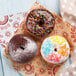 A group of donuts with sprinkles and powdered sugar on a natural kraft basket liner.