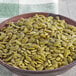 A bowl of raw pumpkin seeds on a table.
