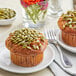 A plate with a muffin topped with raw pumpkin seeds.