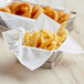 A basket filled with fries and onion rings with white EcoChoice deli wrap inside.
