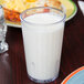 A close up of a GET Clear SAN Plastic tumbler filled with milk on a table.
