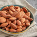 A bowl of roasted unsalted almonds on a napkin.