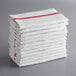 A stack of white towels with red stripes.