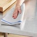 A hand wiping a table with a blue-striped herringbone kitchen towel.