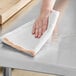 A hand wiping a counter with a white Choice herringbone kitchen towel.
