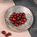 A plate of cranberries on a table with a Denali knotwood embossed design.