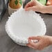 A hand holding a Curtis paper coffee filter over a counter.