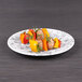 An Elite Global Solutions black marble embossed melamine plate with meat and vegetables on a table.