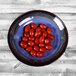 A cobalt blue Elite Global Solutions Monet melamine bowl filled with cherry tomatoes on a wooden table.