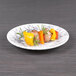 An Elite Global Solutions black marble embossed melamine plate with food on a table.