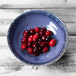 An Elite Global Solutions indigo melamine bowl filled with cranberries on a blue speckled table.