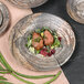 A Denali knotwood embossed melamine plate with meat and vegetables on it on a table.