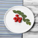 An Elite Global Solutions white melamine plate with red berries and leaves on it.