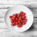 A white Elite Global Solutions Melamine bowl filled with cherry tomatoes.