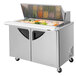 A Turbo Air 2 door refrigerated sandwich prep table with a stainless steel top and food in it.