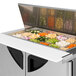 A Turbo Air sandwich prep table with food trays of vegetables.