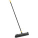 A Quickie bulldozer push broom with a long yellow handle.