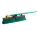 A Quickie Bulldozer green multi-surface push broom with a yellow handle.