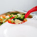 A red Cambro perforated salad bar spoon with vegetables on it.