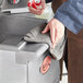 A person cleaning stainless steel with a Quickie microfiber cloth.