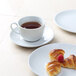 A Tuxton bright white round china cup of tea on a saucer with croissants.
