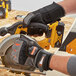 A gloved hand using a circular saw with yellow Ergodyne ProFlex heavy duty gloves.