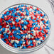 A bowl of Patriotic Star Sprinkles in red, white, and blue on a counter.