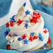 A cupcake with white frosting and red, white, and blue star sprinkles on top.