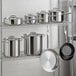 A Vollrath stainless steel rack with Optio cookware set pots and pans.