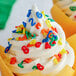 A close-up of a frosted cupcake with Rainbow Number Sprinkles on top.