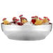 A white American Metalcraft double wall stainless steel bowl filled with ice, soda bottles, and jars of liquid.
