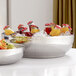 An American Metalcraft hammered stainless steel bowl filled with fruit and juice on a hotel buffet table.