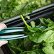A person using Thunder Group green tongs to serve themselves spinach from a plate.