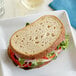 A sandwich made with Schar Gluten-Free Deli Style Sliced Sourdough Bread on a white plate.