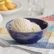 A deep sea cobalt Acopa Capri stoneware bowl filled with ice cream on a table.