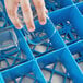 A hand placing a glass into a Carlisle blue tilted cup rack.