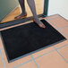 A woman standing on a black Cactus Mat anti-fatigue entrance mat.